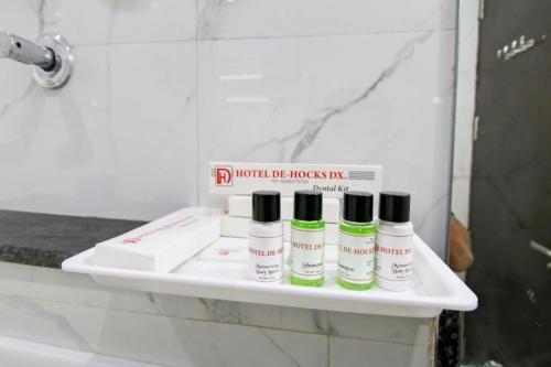 a shelf in a bathroom with four bottles on it at Hotel De Hocks Deluxe - New Delhi Railway Station in New Delhi