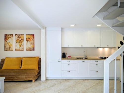 a kitchen with white cabinets and a couch at Cozy house for family and friends in Gargždai