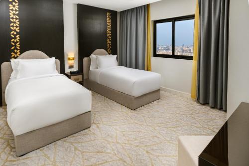 a hotel room with two beds and a window at The Address Serviced Apartments in Al Khobar
