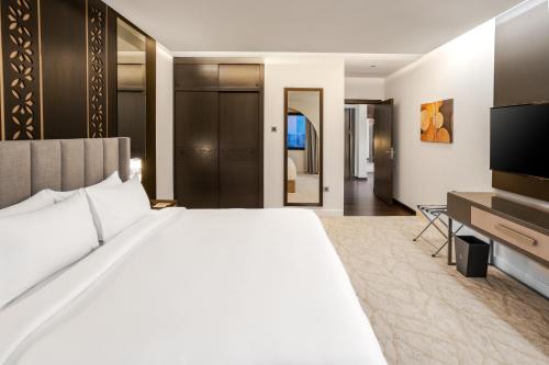 a hotel room with a large bed and a television at The Address Serviced Apartments in Al Khobar