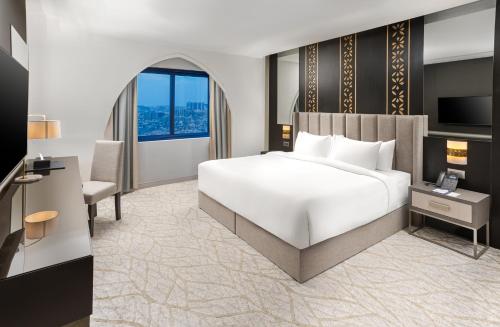 a bedroom with a large white bed and a desk at The Address Serviced Apartments in Al Khobar