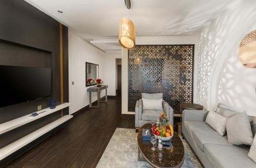 a living room with a couch and a tv at The Address Serviced Apartments in Al Khobar