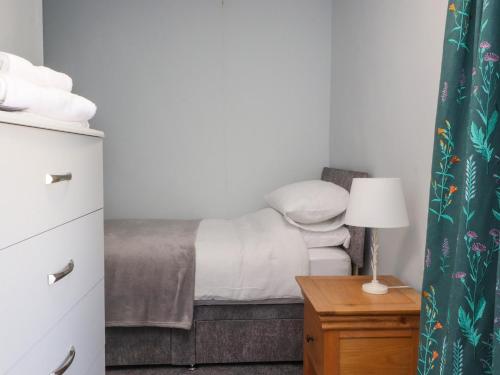 a bedroom with a bed and a table with a lamp at 3 Cowper Place in Clitheroe