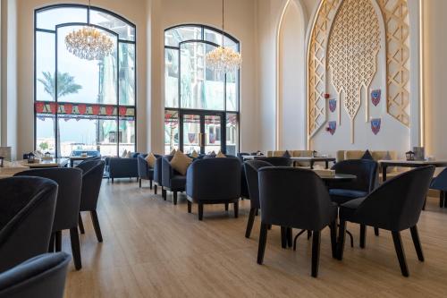 a dining room with chairs and tables and windows at The Address Serviced Apartments in Al Khobar