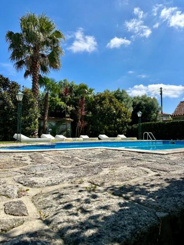a blue swimming pool with a palm tree in the background at Residência das Louras in Viana do Castelo