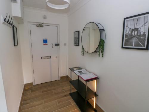 a hallway with a mirror and a table and a door at 34 Croft Court in Tenby