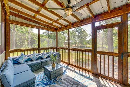 a screened in porch with a couch and a ceiling fan at Quitman Lakefront Cabin with Screened Porch and Grill! in Quitman