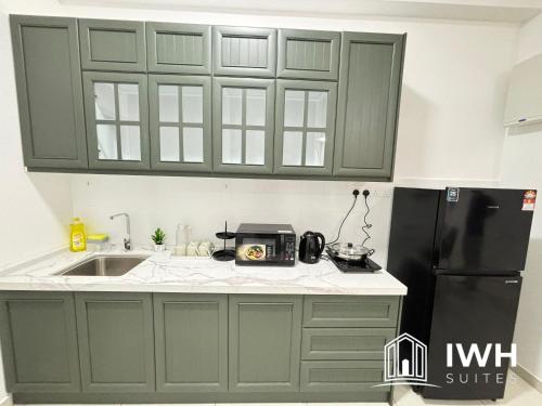 a kitchen with green cabinets and a black refrigerator at Ipoh Horizon Skypool Town Suites 4-11pax by IWH Suites in Ipoh
