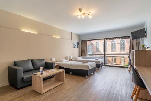 a hotel room with two beds and a couch at Value Stay Residence Mechelen in Mechelen