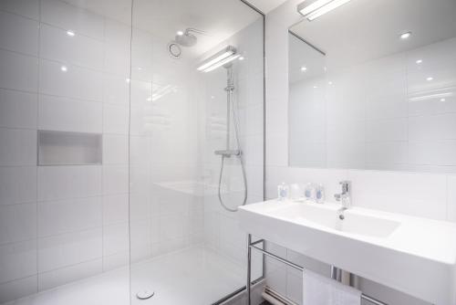a white bathroom with a shower and a sink at Kyriad Le Bourget Centre- Parc Des Expositions in Le Bourget