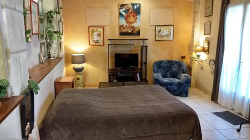 une chambre avec un lit, une chaise et une télévision dans l'établissement Logement tranquille et frais proche gare au RDC, à Saumur