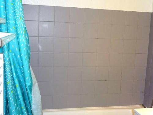 une douche avec un rideau de douche bleu dans une salle de bain dans l'établissement Appartement Confortable 2 Pièces + Cabine, 5 Pers. - Centre Les Gets, Parking Inclus - FR-1-802-60, aux Gets