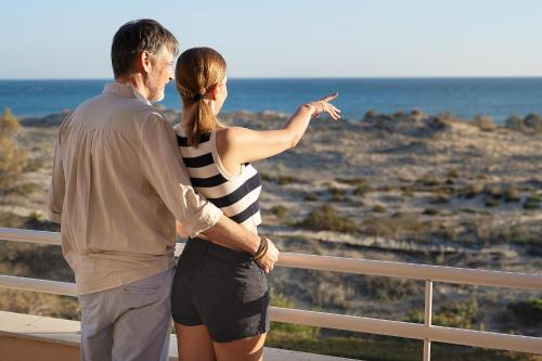 a man and woman standing on a balcony looking at the ocean at Oliva Nova Beach & Golf Hotel in Oliva