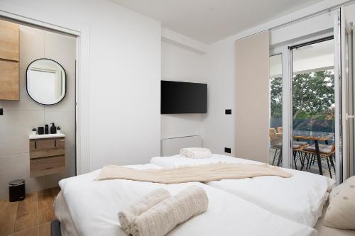 ein weißes Schlafzimmer mit zwei Betten und einem Spiegel in der Unterkunft Villa Blue Banjole in Banjole