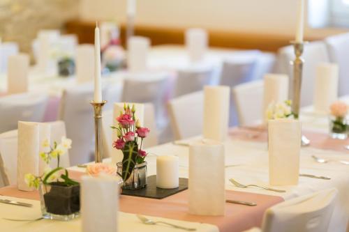 a table with white candles and flowers on it at Hotel Germania in Stadtallendorf