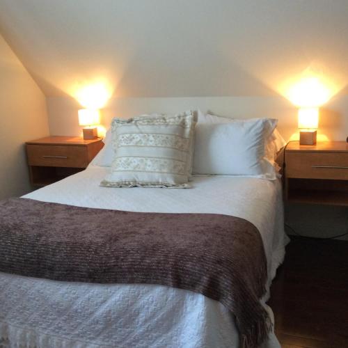 a bedroom with a bed with pillows and two lamps at Les Chalets Baie Cascouia in Lac Kénogami