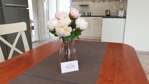 a vase filled with pink roses sitting on a table at Éden Villa Apartmanház in Balatonfüred