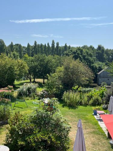 Elle offre une vue sur un jardin planté d'arbres et de buissons. dans l'établissement Auberge de la chesnaie, à Pleudihen-sur-Rance