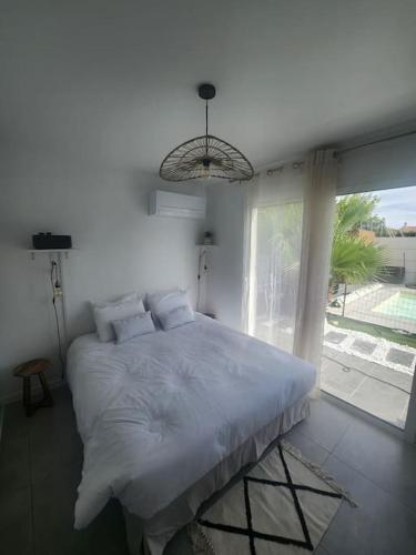une chambre blanche avec un grand lit et une fenêtre dans l'établissement Chambre Armelle, chambre privée avec accés piscine, à Artigues-près-Bordeaux
