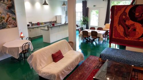 un salon avec un canapé et une table et une cuisine dans l'établissement Logement spacieux et original proche gare au RDC, à Saumur