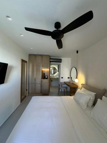 a bedroom with a large white bed with a ceiling fan at Petinaros Hotel in Mýkonos City