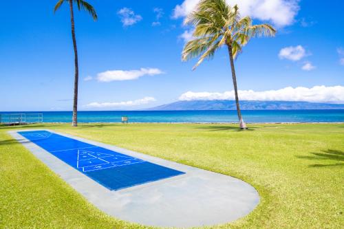 a blue basketball court next to the ocean with palm trees at Papakea E404 in Kahana