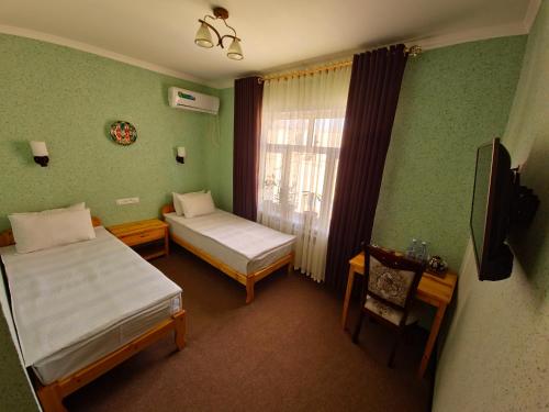 a small room with two beds and a window at Islam Khodja in Khiva