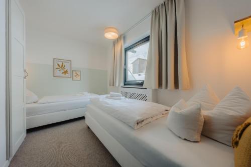 a white room with a bed and a window at Hotel Pfeifer in Gaschurn