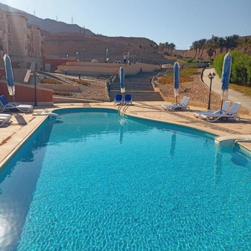 a large blue swimming pool with chairs and umbrellas at Porto Sokhna Heaven Hills Chalet Families ONLY in Ain Sokhna