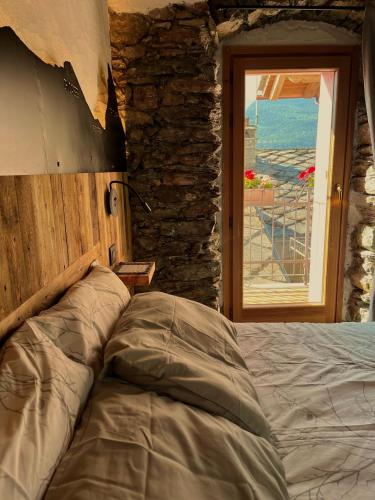 a bed in a room with a stone wall and a window at La famille d'Evian in Villeneuve