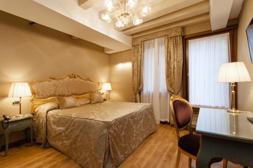 a bedroom with a bed and a table and a chandelier at Hotel Al Ponte Mocenigo in Venice