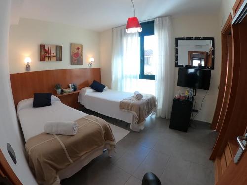 una camera d'albergo con due letti e una televisione di Sitges rooms by Sitges Apartment a Sitges