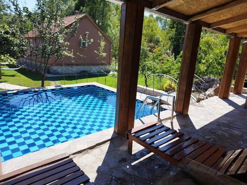 a swimming pool with a bench and a house at Forest Home in Golubovci