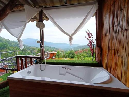 a bath tub in front of a window with a view at บ้านลิ้นจี่โฮมสเตย์ Baan Lychee homestay in Ban Thung Phan Ha
