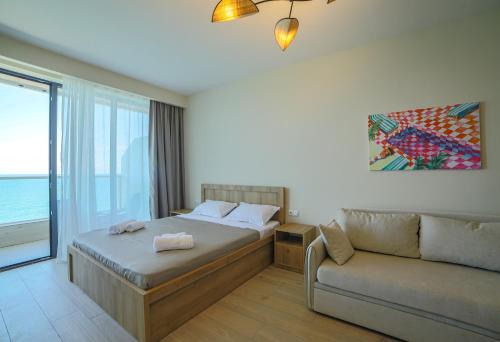 a bedroom with a bed and a couch and a window at Cozy, comfortable apartment at Bamboo Beach Tsikhisdziri in K'obulet'i