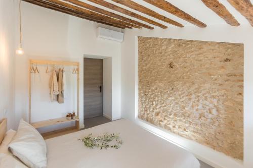 a bedroom with white walls and a large stone wall at Mas d'en Jan in Roquetas