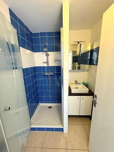 La salle de bains est pourvue de carrelage bleu, d'une douche et d'un lavabo. dans l'établissement Appartement Cap d'Agde vue port, au Cap d'Agde