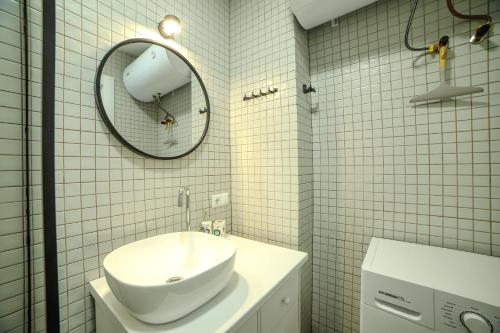 a white tiled bathroom with a sink and a mirror at Cozy, comfortable apartment at Bamboo Beach Tsikhisdziri in K'obulet'i