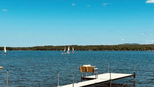 a dock with a chair and sailboats on a lake at La vie O-Lac Magog in Sherbrooke