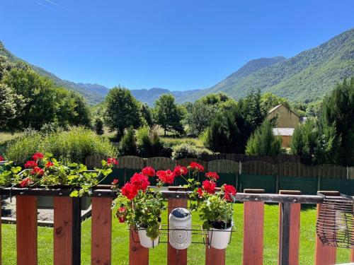 a fence with red flowers in potted plants at Mountain view 2-bedroom Pyrenees apartment in Saint-Béat