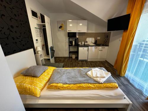 a bedroom with a bed with yellow sheets and a kitchen at See Panzió in Fertőrákos