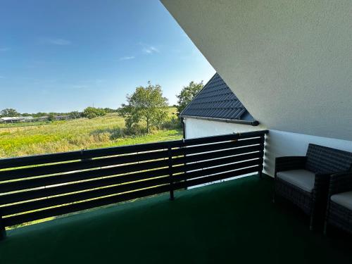 a balcony with two chairs and a view of a field at See Panzió in Fertőrákos