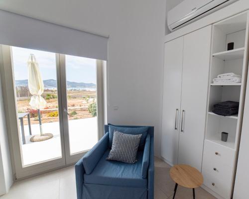 a living room with a blue couch and a large window at CAMPO SUITES in Kampos Paros