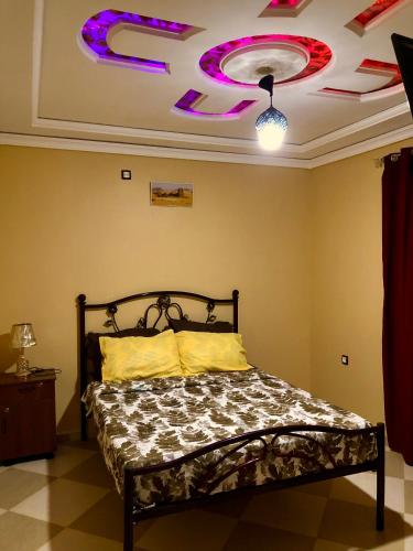 a bedroom with a bed and a ceiling with purple lights at Le Garden Ghardaia in Ghardaïa