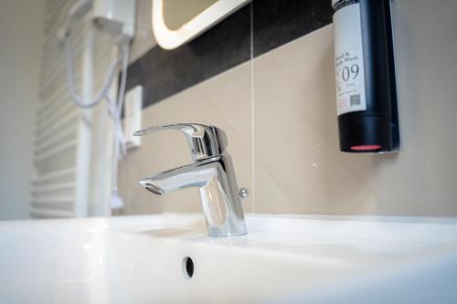 ein Waschbecken mit einem Wasserhahn und einer Flasche Seife in der Unterkunft Moderne Apartments City Stadtnah -JUNIK Apartments in Duisburg