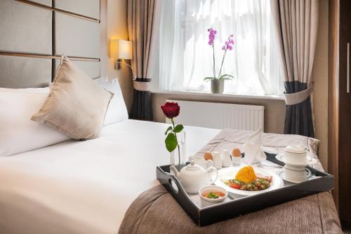 a tray of food on a bed in a hotel room at Gem Langham Court Hotel in London