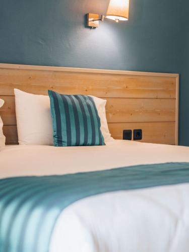 a bed with a blue and white pillow on it at Hotel Mas Des Barres in Saintes-Maries-de-la-Mer