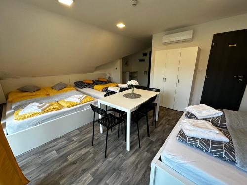 a room with three beds and a table and chairs at See Panzió in Fertőrákos