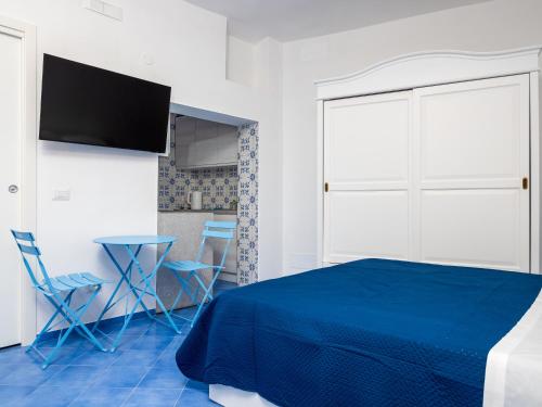 a bedroom with a blue bed and a table and chairs at De Vivo Realty - Camilla House Positano in Positano
