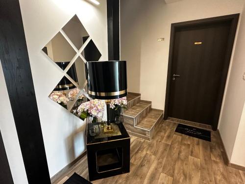 a hallway with a black door and a vase of flowers at See Panzió in Fertőrákos